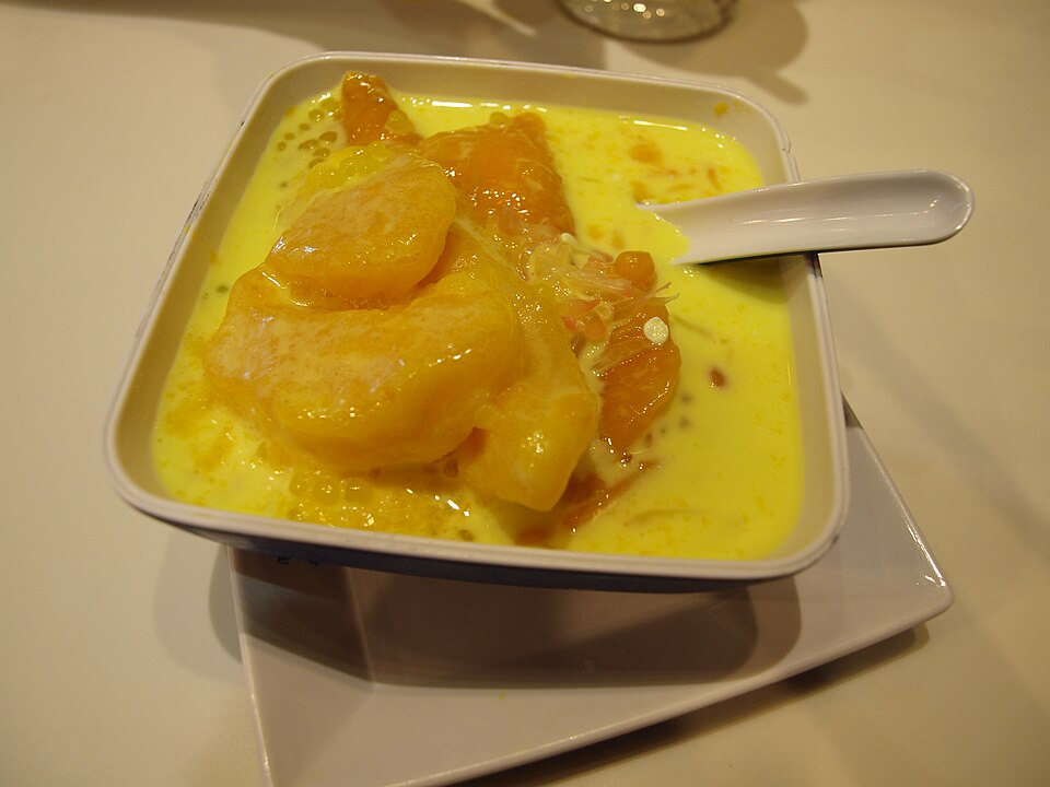 A square bowl of mango pomelo sago: yellow mango pieces, pomelo and tiny sago pearls in a creamy mango base