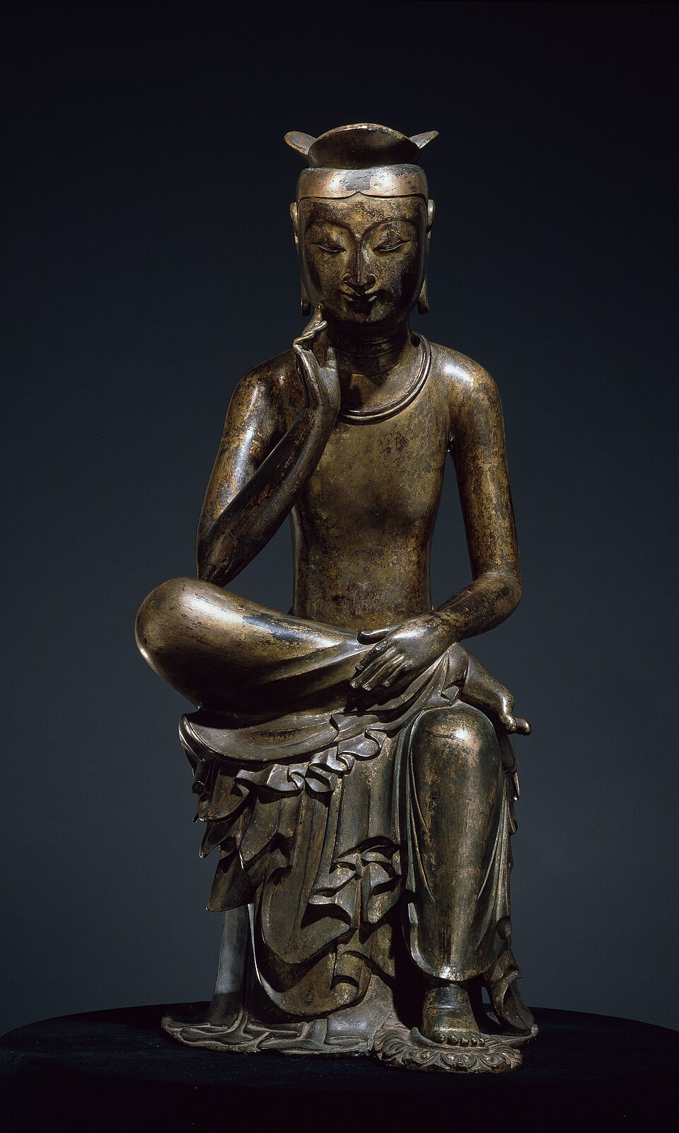 The gilt-bronze Pensive Bodhisattva, a slim seated figure with one leg crossed and a hand raised to the cheek